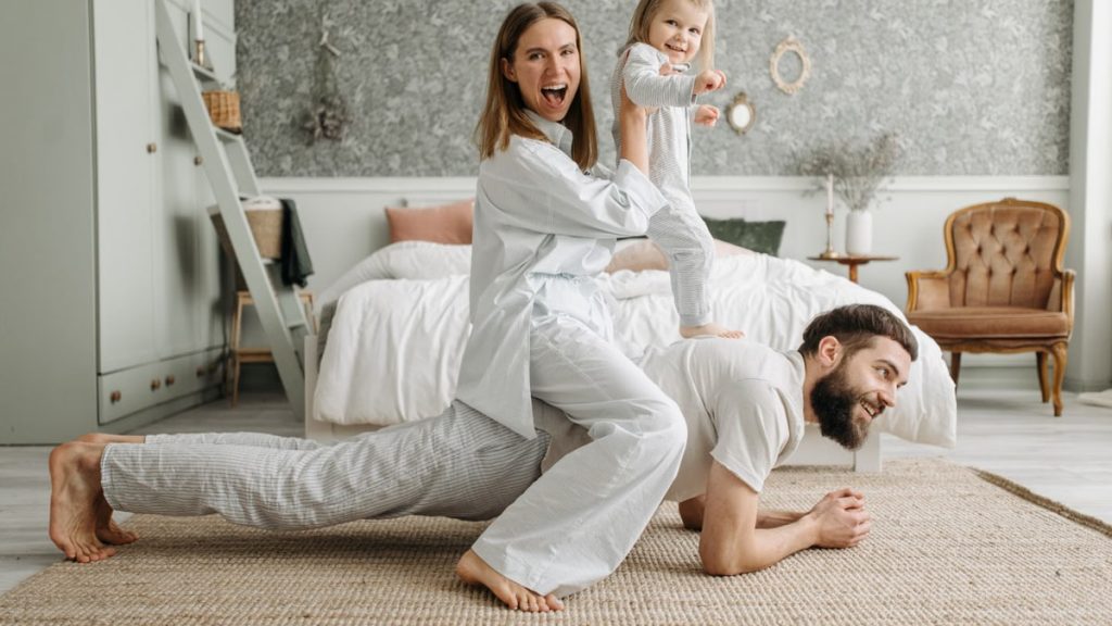 A cheerful family enjoys bonding and playing together on a cozy morning in a stylish bedroom.