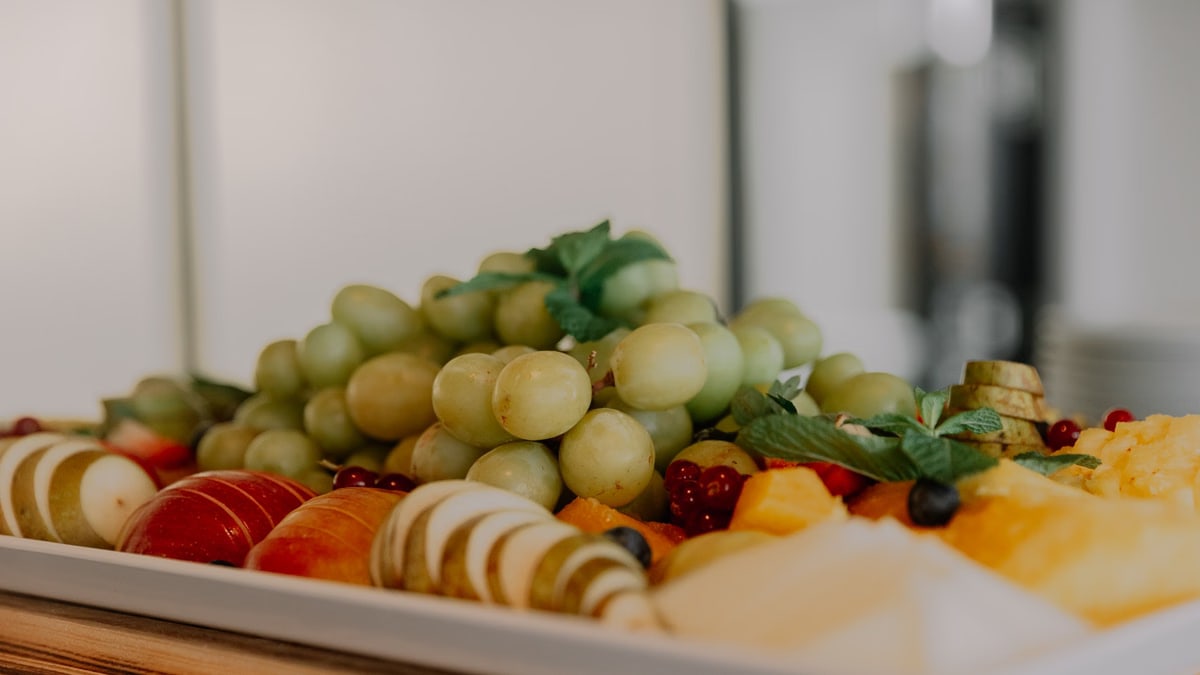A vibrant assortment of fruits including grapes, apples, and berries on a white tray.